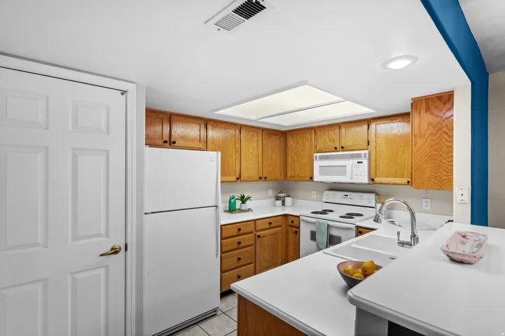 Kitchen featuring wood cabinetry, white countertops, built-in microwave, and a double basin sink