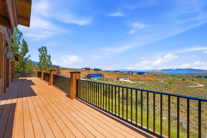 Expansive outdoor deck featuring wood-finish flooring and black metal railings with wood posts