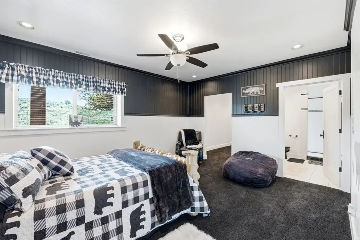 Room featuring dark paneled wainscoting, white walls, and dark carpet flooring