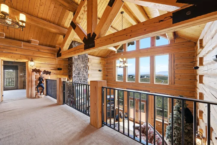 Loft area showcasing exposed wood beams, log walls, and a stone-clad fireplace