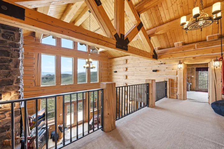 Open-concept upper level featuring exposed wood beams and log walls