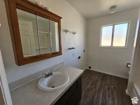 Bathroom featuring wood-finish flooring, a white vanity with a light-toned countertop, and a medicine cabinet with a wood-tone frame