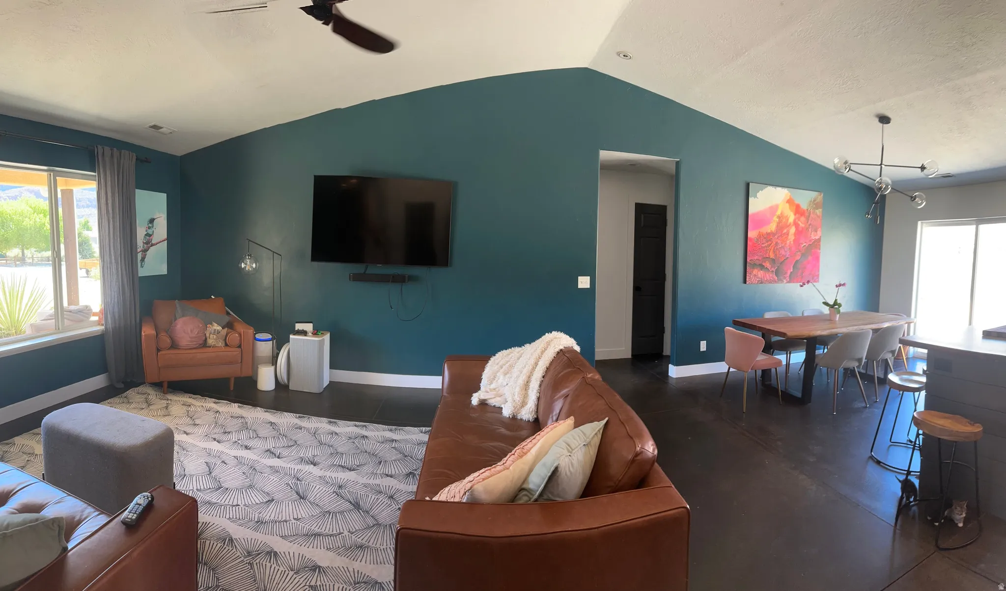 Open-concept living and dining area with vaulted ceiling and fan