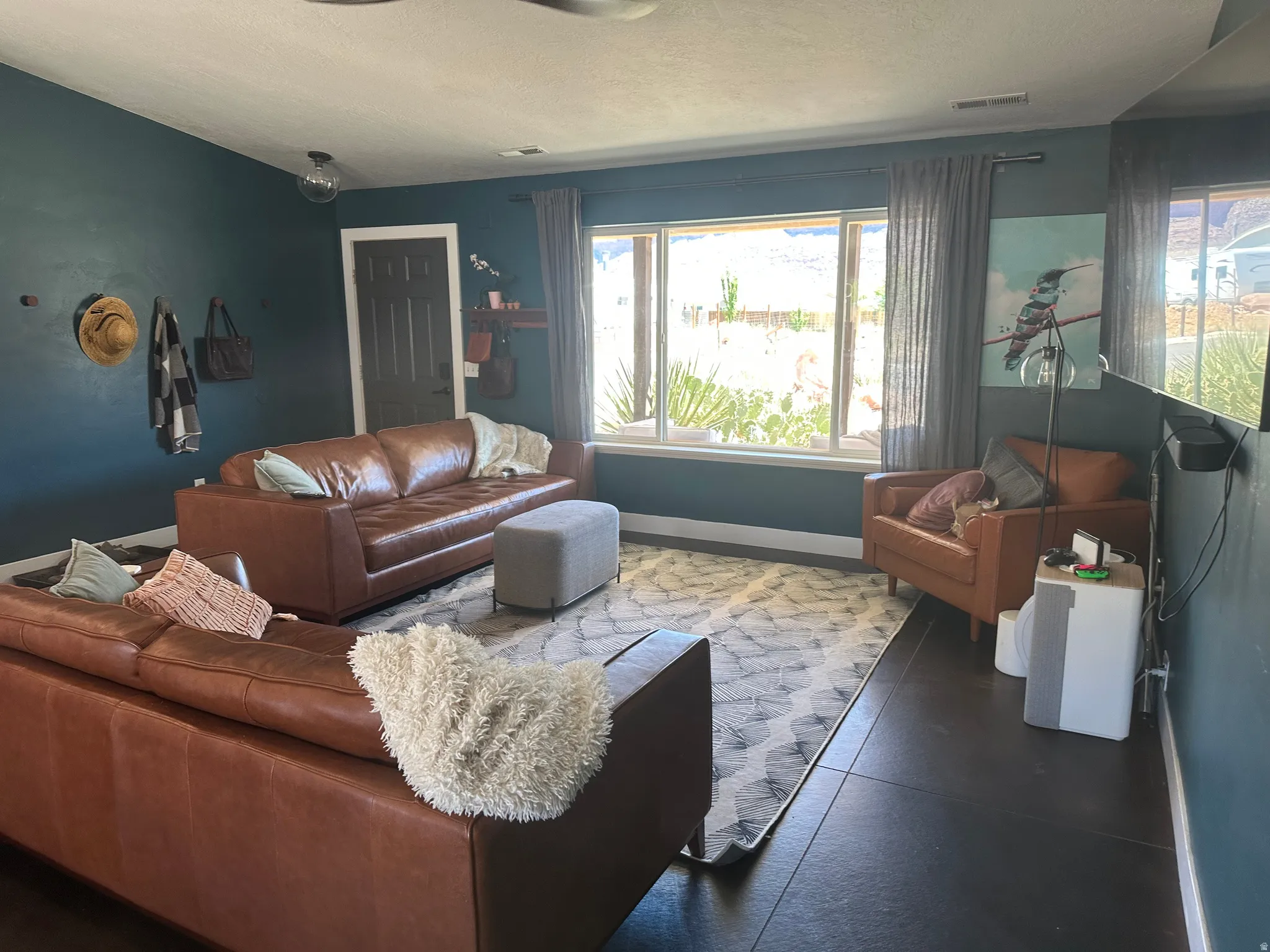 Spacious living area with large window, vaulted ceiling with fan and stained concrete flooring