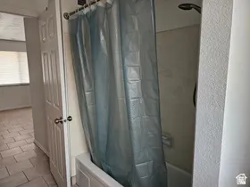 Tub/shower combination featuring a chrome showerhead and a light-toned tile surround