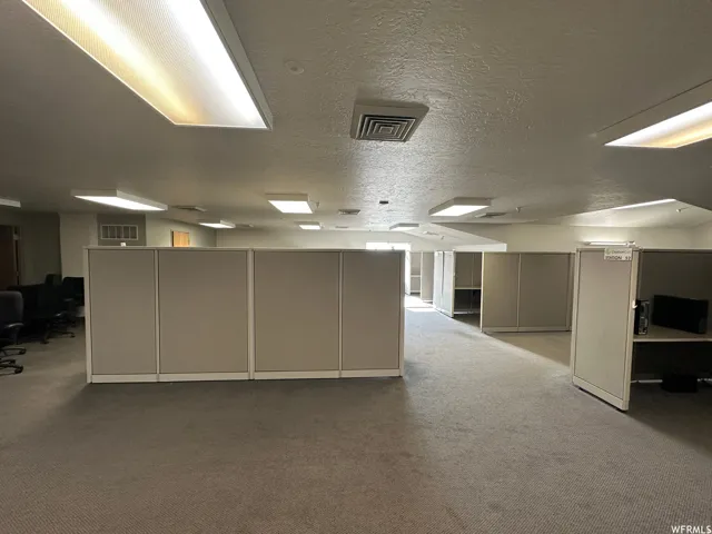 Open-plan office space featuring modular cubicles, recessed lighting, and textured ceilings