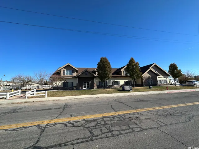 Multi-level building with gabled rooflines, stone and siding exterior, and multiple windows with dark shutters