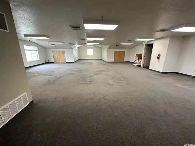 Spacious carpeted room featuring multiple windows, recessed lighting, and access doors