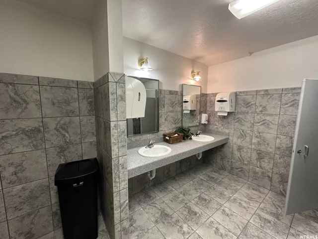 Public restroom featuring gray marble-look tile flooring and wainscoting