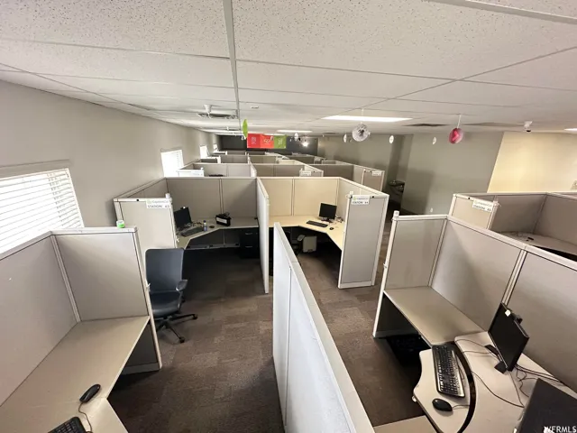 Open-concept commercial space featuring multiple workstations with partition walls, recessed lighting, and a drop ceiling