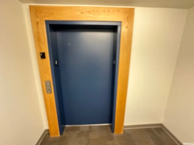 Elevator access featuring a blue door with wood-finish trim and integrated call buttons