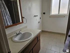 Bathroom featuring a vanity with an integrated sink, a medicine cabinet, tile flooring, and a window with privacy glass