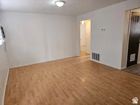 Spacious room featuring wood-finish flooring, white painted walls, and a flush mount ceiling light fixture