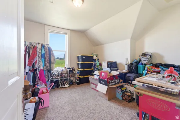 Carpeted room with a single window and sloped ceilings