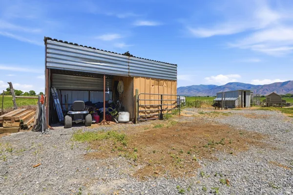 Open-sided utility shed with a corrugated metal roof and wood siding