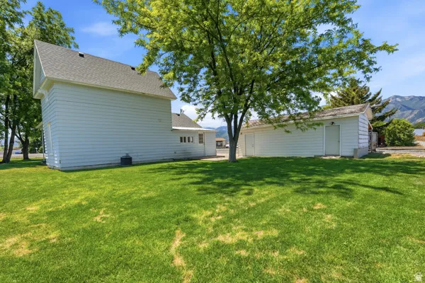 Expansive green lawn surrounds the property, featuring a detached garage with multiple access doors