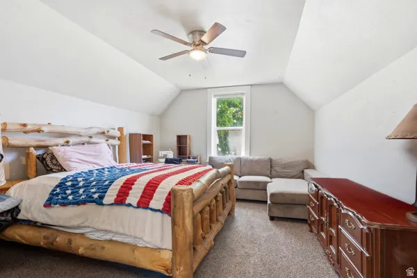 Carpeted room with a vaulted ceiling and a ceiling fan