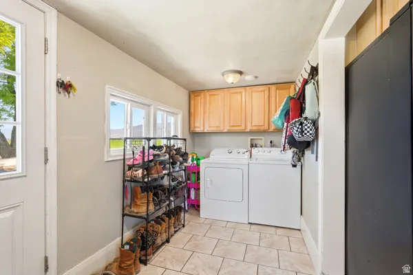 Utility area featuring light wood-finish cabinetry, a washer and dryer, and tiled flooring