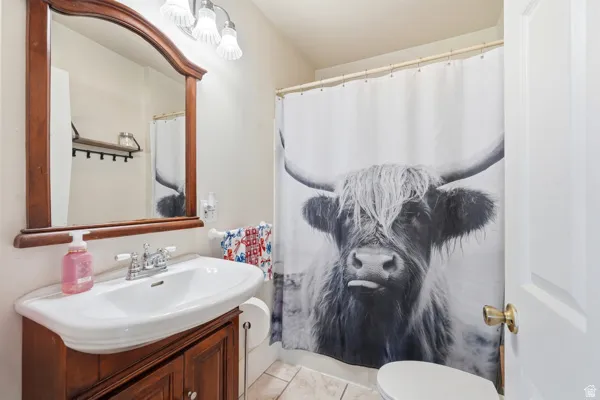 Bathroom featuring a pedestal sink with a wood-finish vanity, a framed mirror, and a three-light vanity fixture