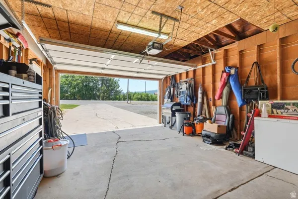 Attached garage featuring a concrete floor, exposed wood framing, and an automatic overhead door