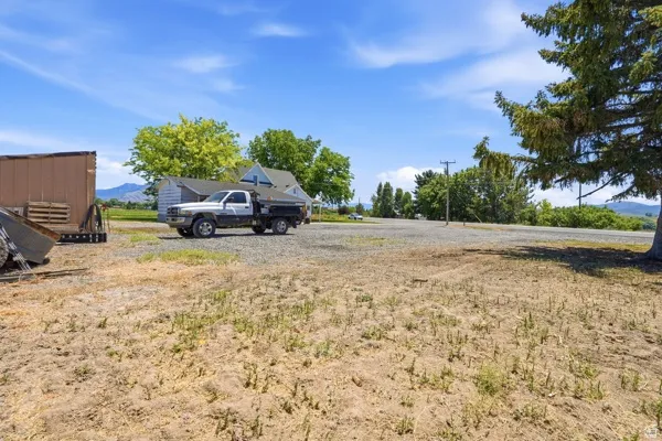 Expansive gravel area with visible mountain backdrop and mature trees
