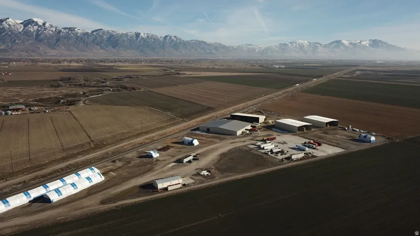 Expansive agricultural property featuring multiple large industrial buildings, a spacious gravel lot, and direct frontage on a paved road