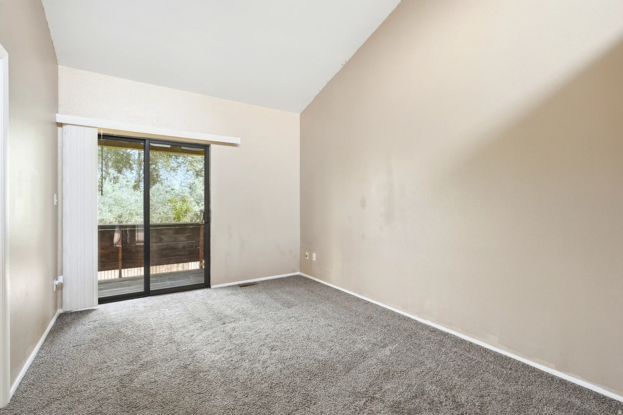 Primary bedroom sliding glass door to an exterior balcony, featuring a paneled wood railing
