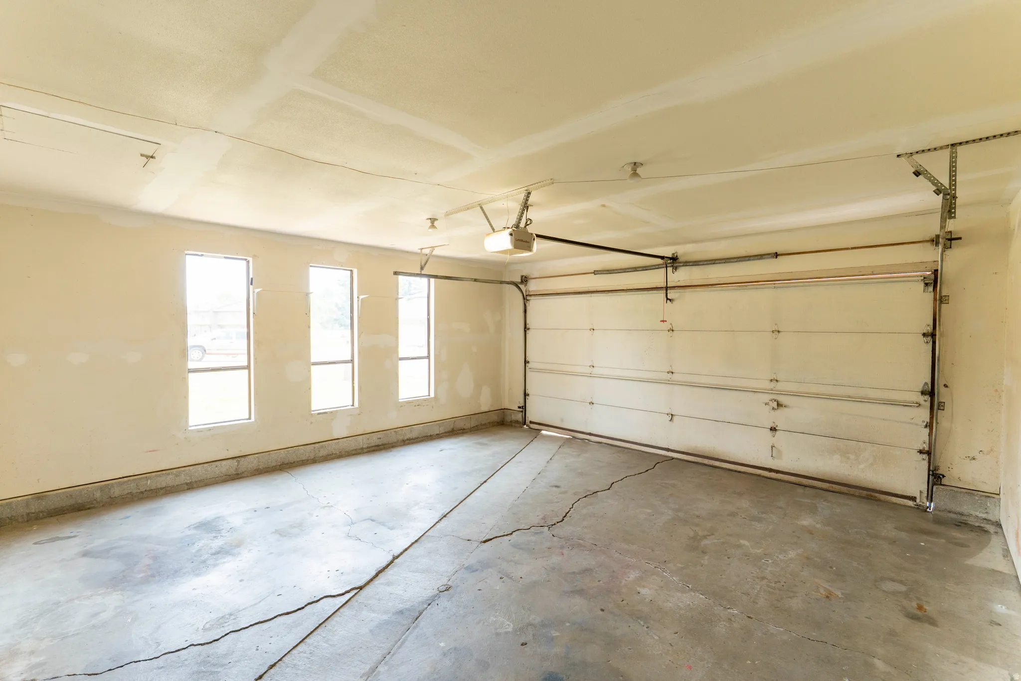 Spacious garage with multiple windows for natural illumination, a concrete floor, and an automatic garage door opener