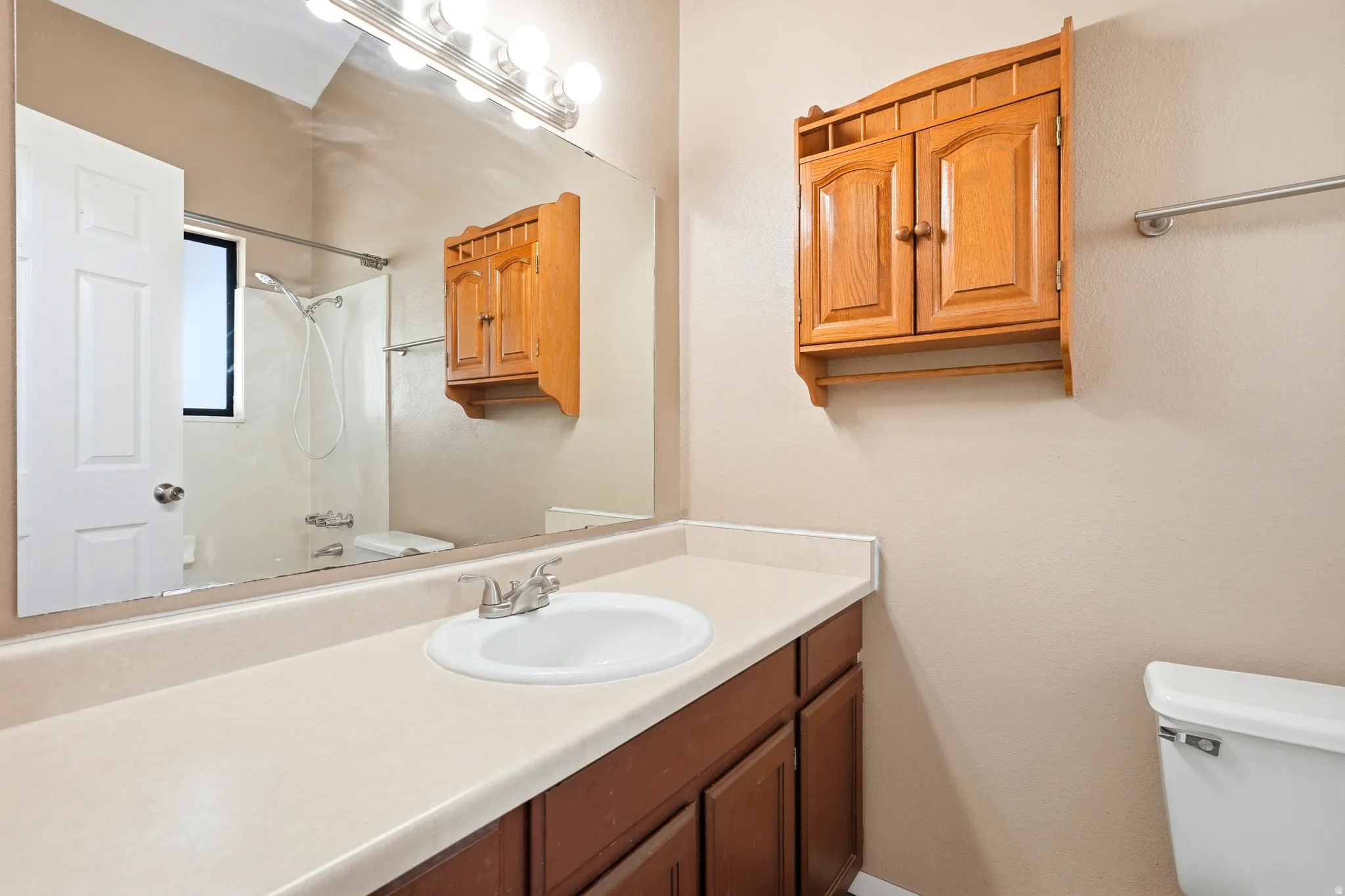 Bathroom vanity featuring a single basin sink, laminate countertop, and wood-finish cabinetry
