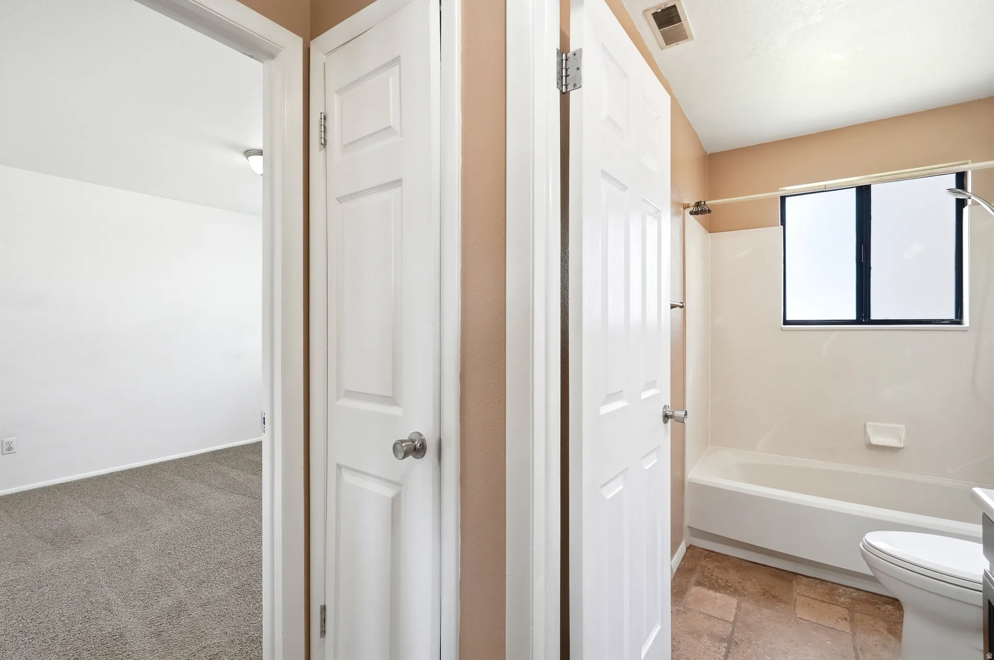 Bathroom featuring a white tub, shower fixture, and a window with dark framing