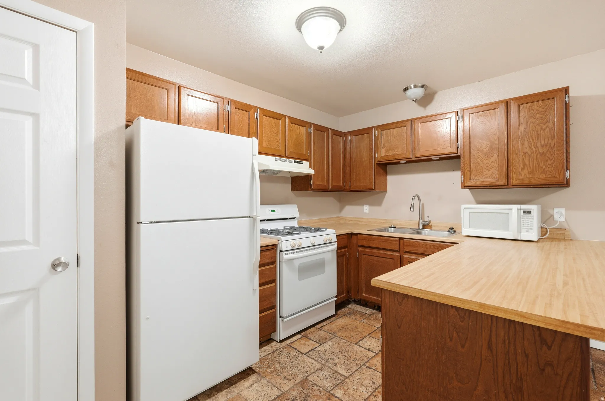 Kitchen featuring wood-finish cabinetry, laminate countertops, and tile flooring