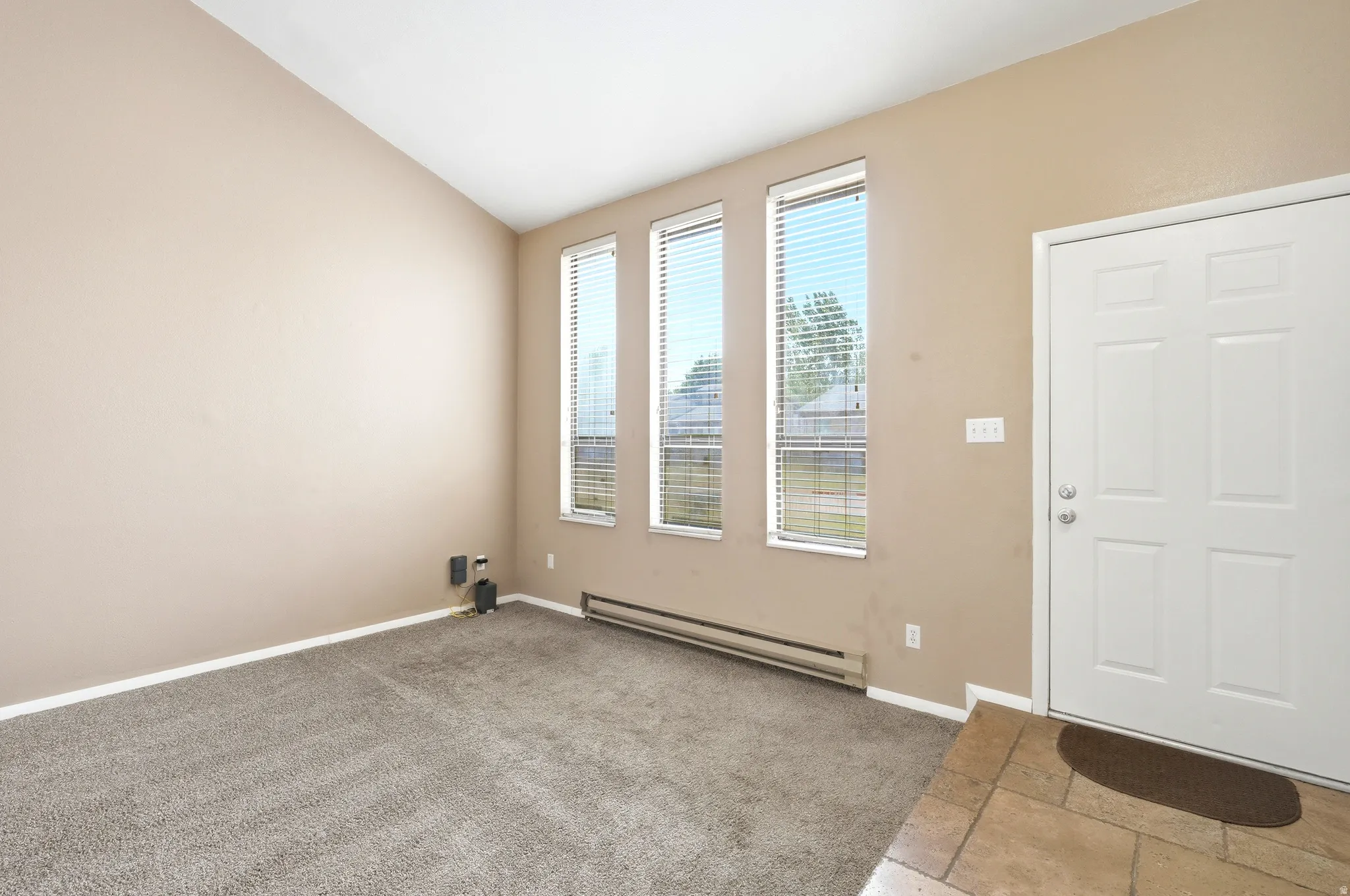 Carpeted living area with vaulted ceilings and three vertical windows