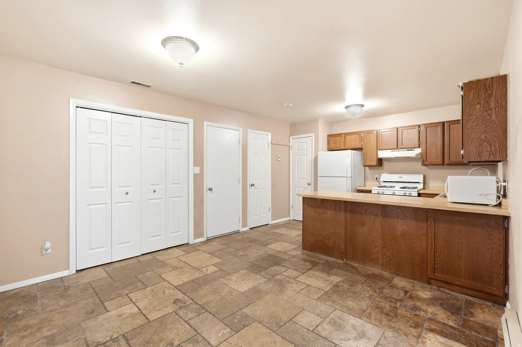 Kitchenette featuring wood-finish cabinetry, a white refrigerator, and a gas range