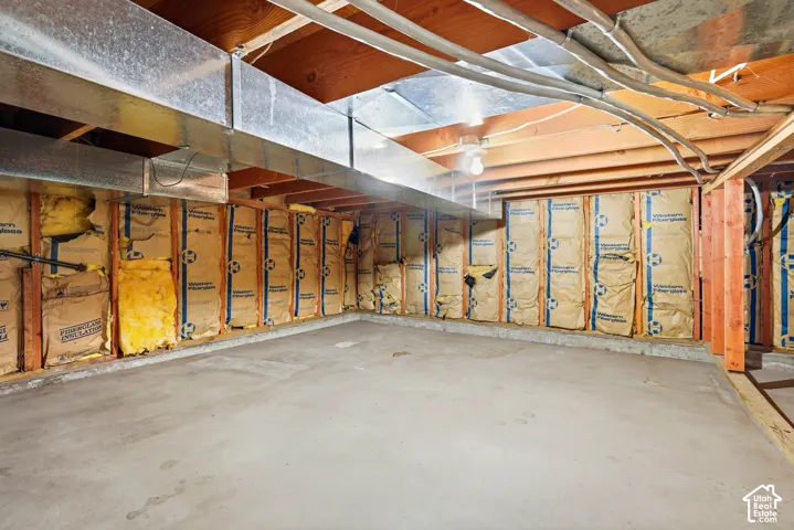 Unfinished crawl space featuring exposed wooden ceiling joists, galvanized ductwork, and insulated wall framing