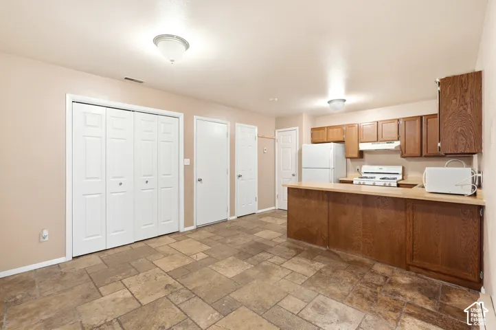 Kitchenette featuring wood-finish cabinetry, a white refrigerator, and a gas range