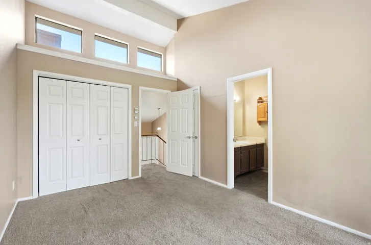 Primary bedroom with vaulted ceilings with exposed beams and upper transom windows