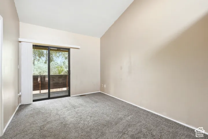 Primary bedroom sliding glass door to an exterior balcony, featuring a paneled wood railing