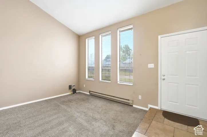 Carpeted living area with vaulted ceilings and three vertical windows