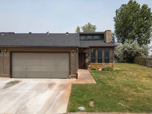 Residence featuring a two-car garage, stone and wood-paneled facade, and a dark asphalt shingle roof