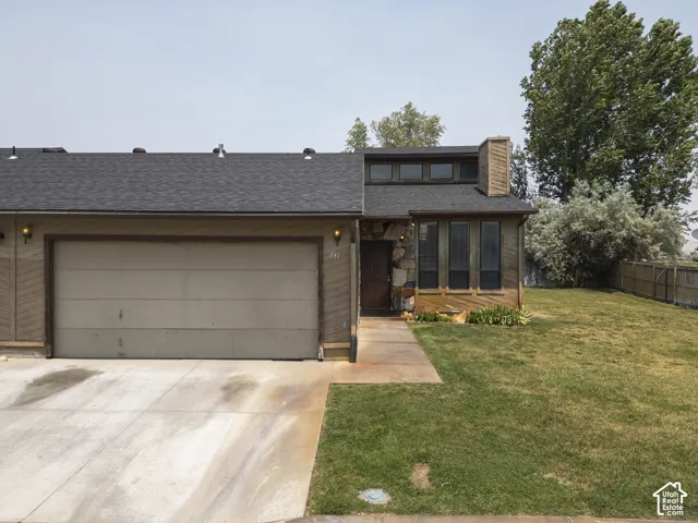 Residence featuring a two-car garage, stone and wood-paneled facade, and a dark asphalt shingle roof