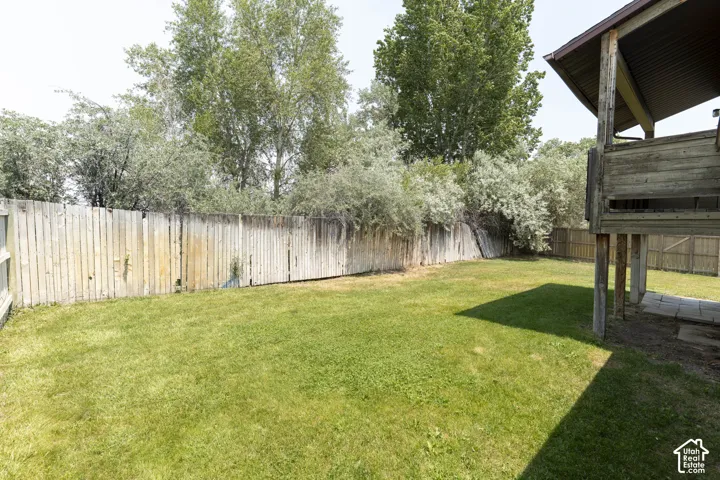Expansive grassy backyard featuring a perimeter fence and mature trees