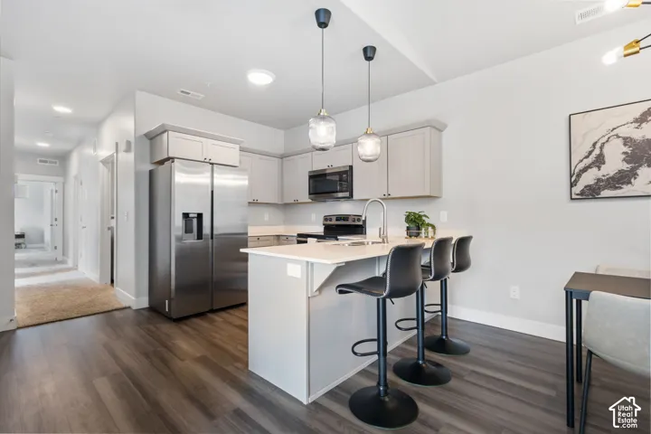 Modern kitchen featuring light gray cabinetry, stainless steel appliances, and a central island with bar seating
