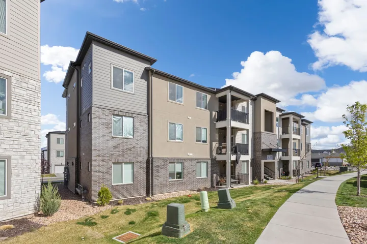 Multi-story residential building featuring a combination of horizontal siding, brick facade, and stucco finishes