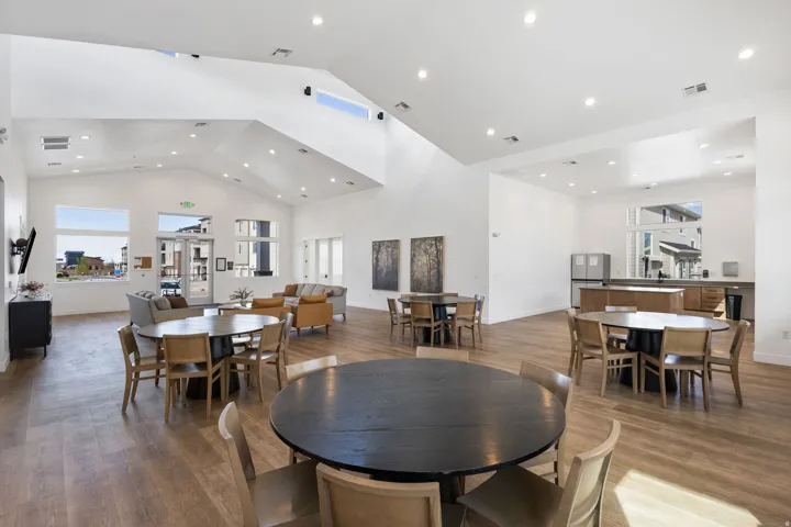 Spacious common area featuring vaulted ceilings, recessed lighting, wood-finish flooring, a full kitchen with stainless steel appliances, and large windows