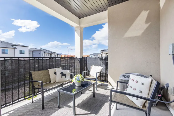 Covered outdoor balcony featuring a textured ceiling, stucco wall finishes, and a black wrought iron railing