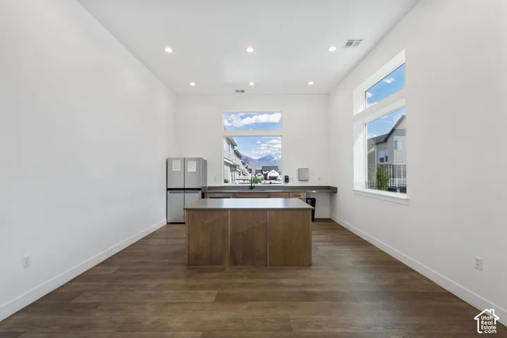 Open concept space featuring wood-finish flooring, a central island with a solid surface countertop, and stainless steel appliances