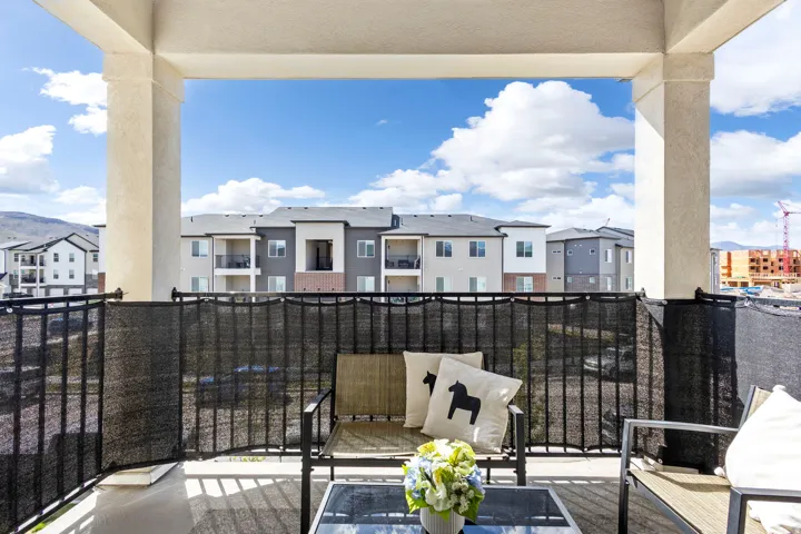 Covered outdoor balcony with sturdy support columns, black metal railings, and a privacy screen