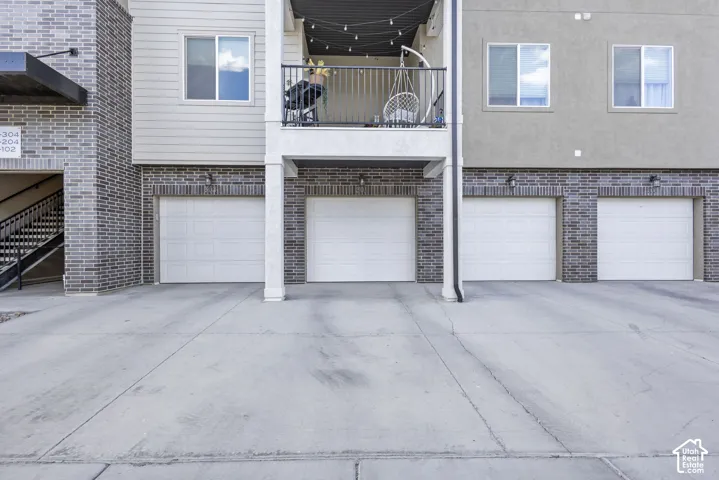 Exterior featuring a combination of brick and siding, multiple garage doors, and a private balcony