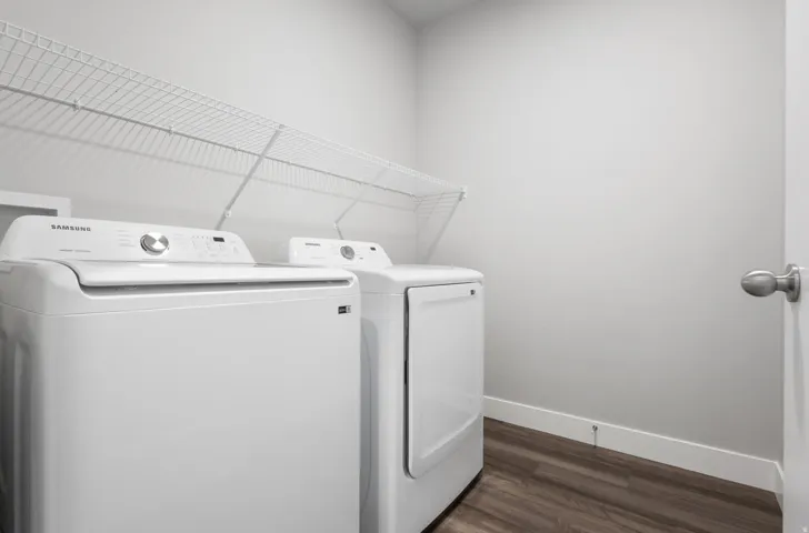 Dedicated laundry area featuring a white wire shelving unit, wood-finish flooring, and a neutral wall color