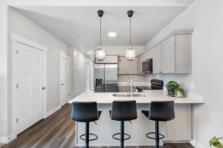 Open-concept kitchen featuring light-toned cabinetry, stainless steel appliances, and a central island with a sink